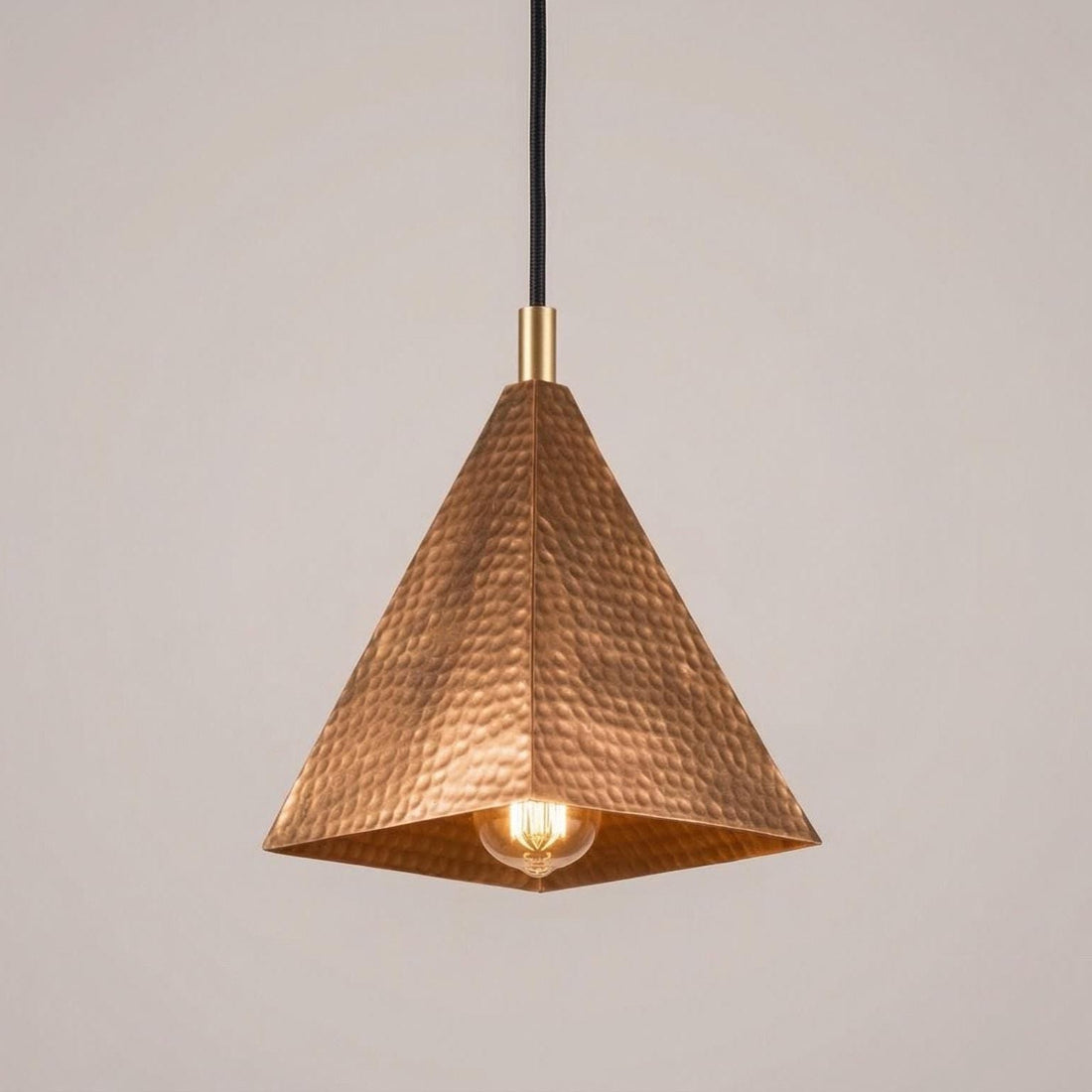 Copper pendant light with textured design on a plain background